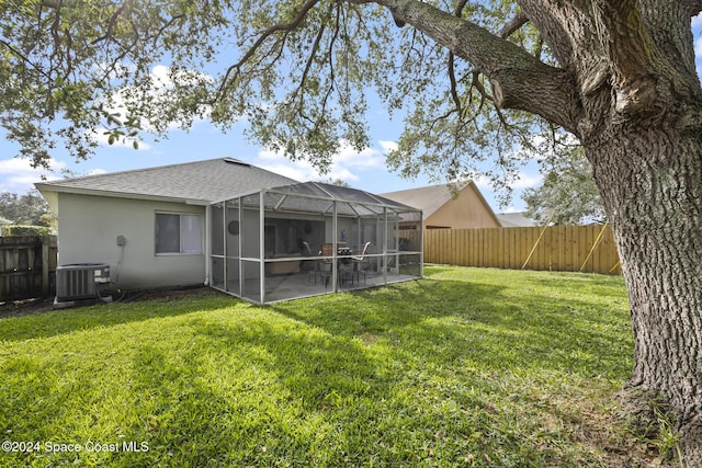 rear view of house featuring a patio, glass enclosure, cooling unit, and a lawn