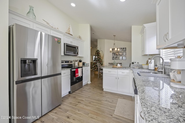 kitchen featuring white cabinetry, sink, decorative light fixtures, vaulted ceiling, and appliances with stainless steel finishes