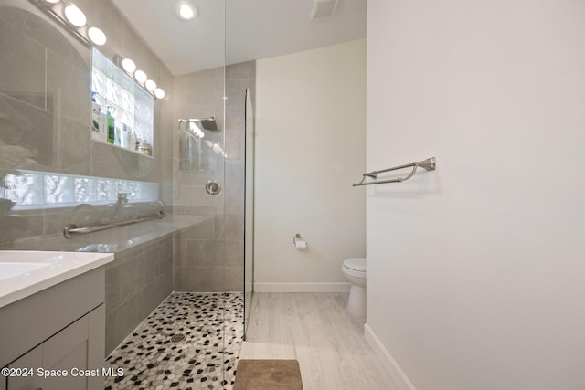 bathroom with hardwood / wood-style floors, vanity, lofted ceiling, and tiled shower