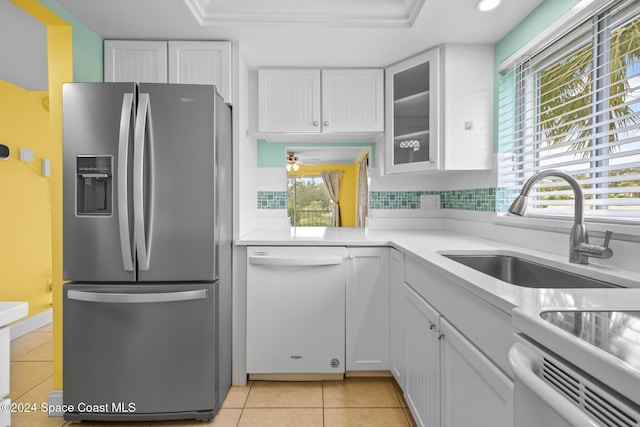 kitchen with white dishwasher, sink, stainless steel fridge, a healthy amount of sunlight, and white cabinetry