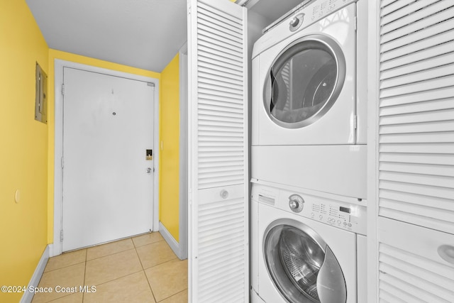 laundry area featuring electric panel, light tile patterned floors, and stacked washer / drying machine