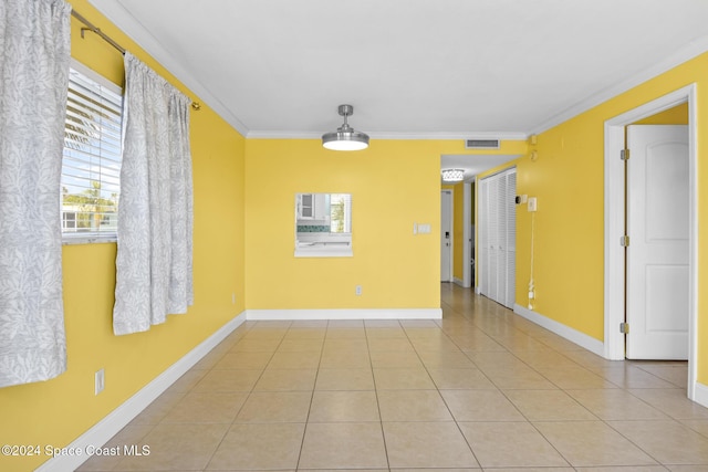 tiled empty room with a healthy amount of sunlight and ornamental molding