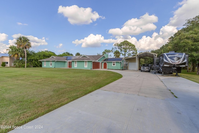 ranch-style home with solar panels, a carport, a front yard, and a garage