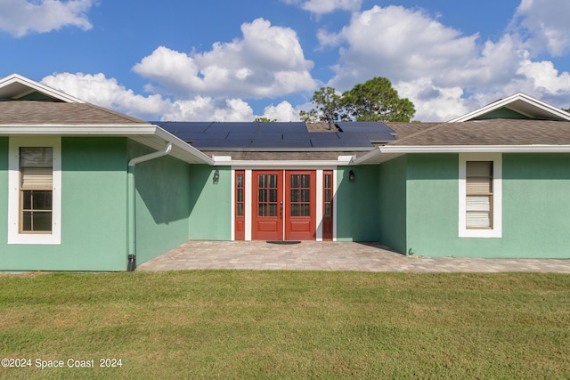 back of property featuring a lawn, solar panels, a patio, and french doors