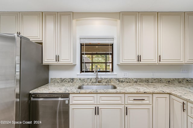 kitchen with cream cabinetry, sink, and stainless steel appliances