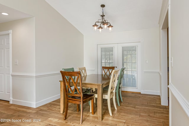 dining area featuring light hardwood / wood-style flooring, lofted ceiling, and an inviting chandelier