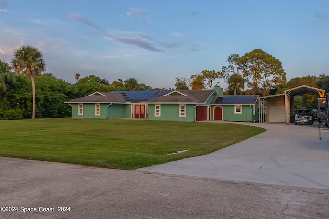 ranch-style house with solar panels, a garage, and a front lawn