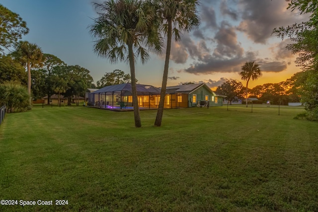 yard at dusk featuring a lanai