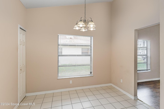 867 S Patrick Dr, Satellite Beach, FL 32937 - unfurnished room featuring plenty of natural light, a chandelier, a high ceiling, and light tile patterned floors
