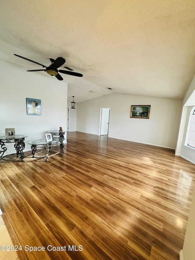 unfurnished living room with ceiling fan, light hardwood / wood-style floors, vaulted ceiling, and a textured ceiling