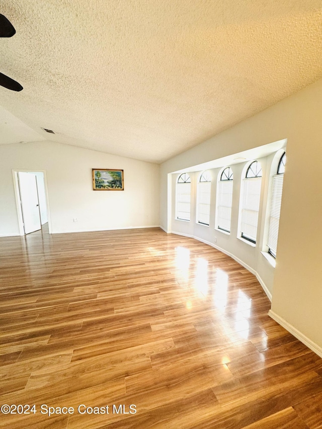 unfurnished living room with wood-type flooring, lofted ceiling, and a textured ceiling