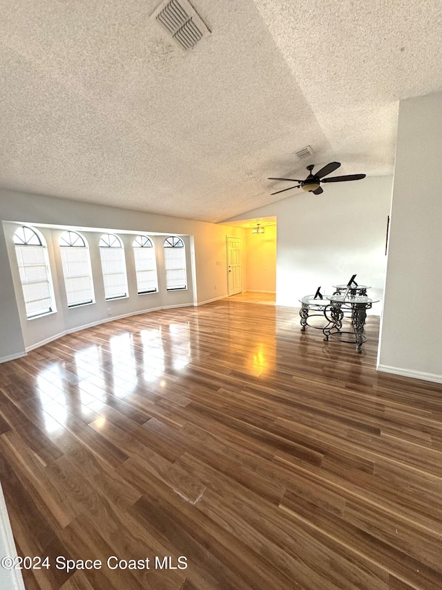 unfurnished living room with lofted ceiling, dark wood-type flooring, and a textured ceiling