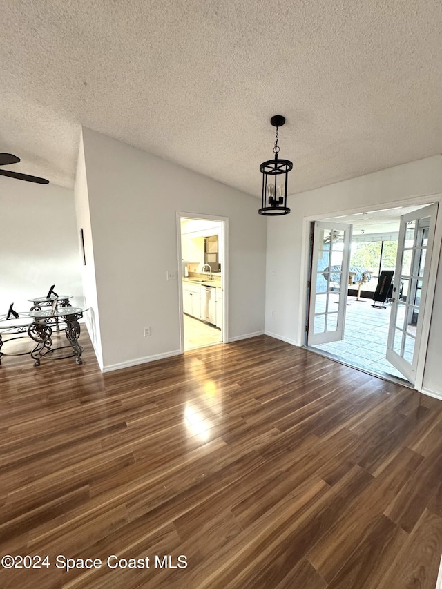 unfurnished dining area with lofted ceiling, a textured ceiling, dark hardwood / wood-style flooring, and french doors