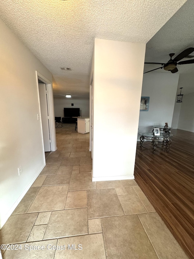 hallway featuring light wood-type flooring and a textured ceiling