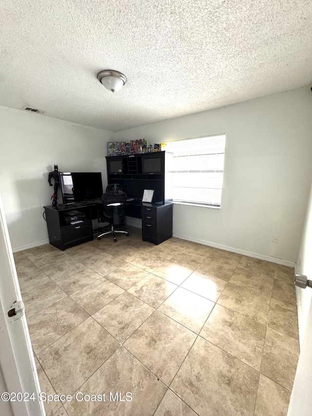 tiled office space with a textured ceiling