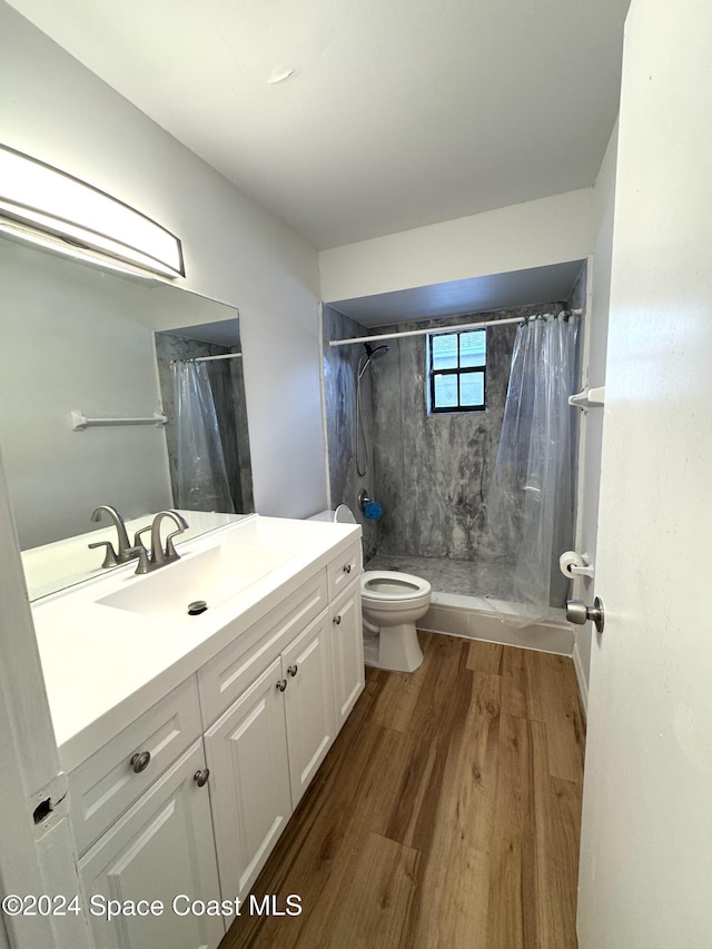 bathroom with hardwood / wood-style flooring, vanity, walk in shower, and toilet