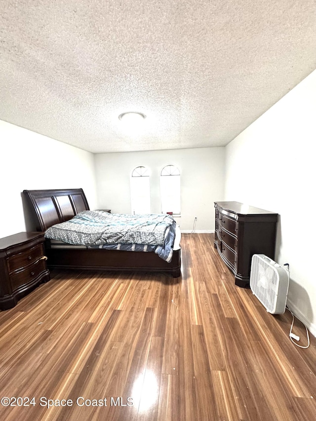 bedroom with dark hardwood / wood-style flooring and a textured ceiling