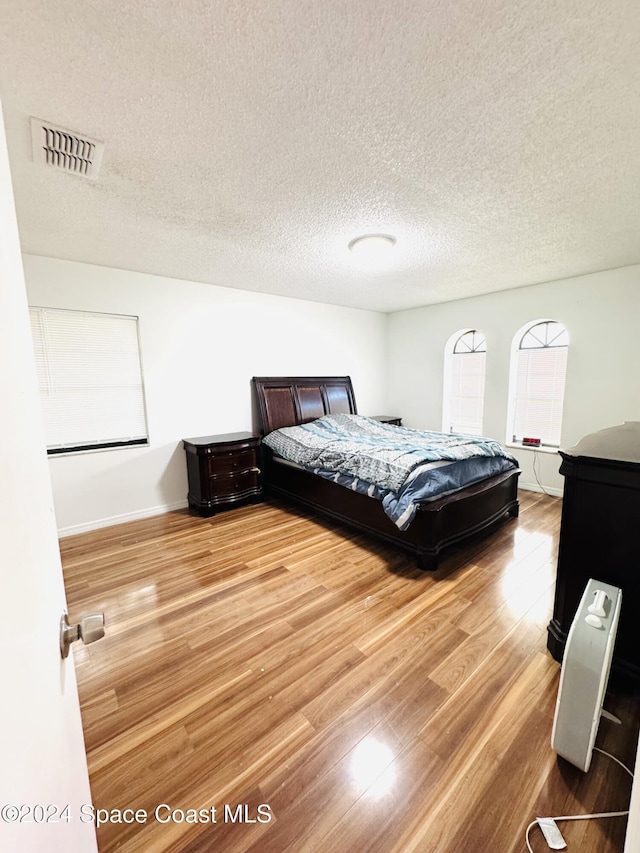 bedroom with wood-type flooring and a textured ceiling