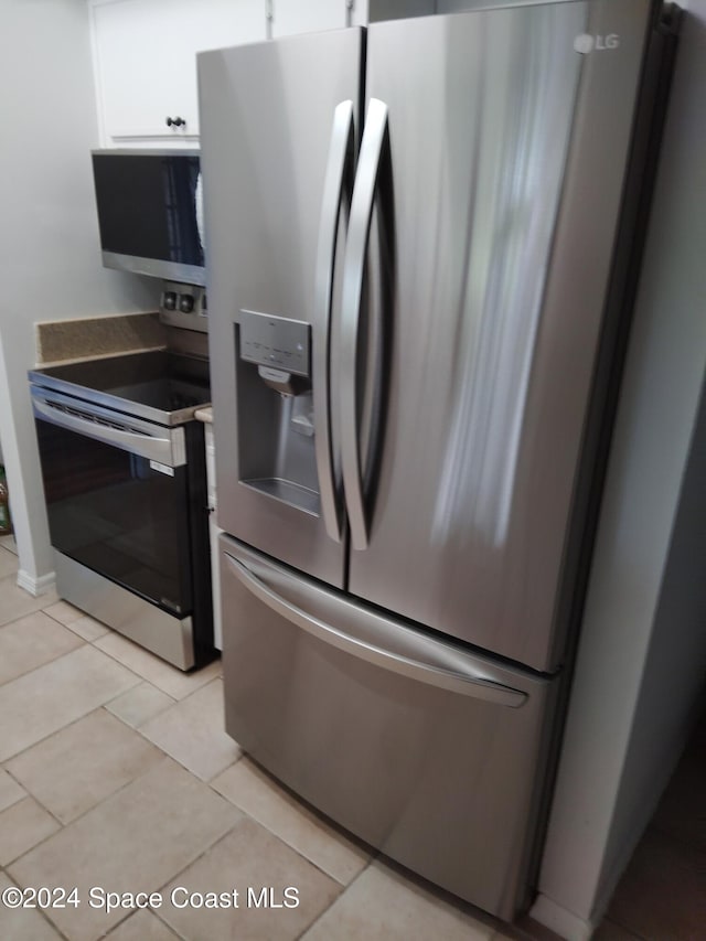 kitchen featuring light tile patterned flooring, white cabinets, and appliances with stainless steel finishes