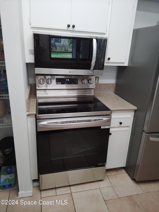 kitchen with stainless steel appliances, white cabinets, and light tile patterned flooring