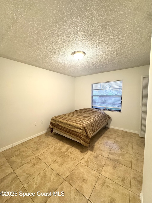 bedroom featuring light tile patterned floors and a textured ceiling