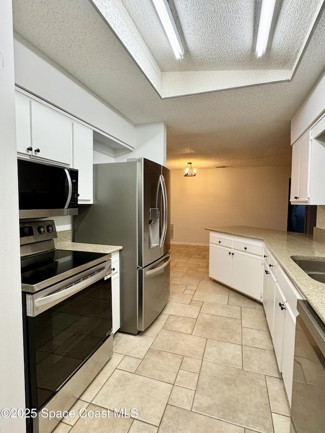 kitchen featuring light tile patterned floors, white cabinetry, stainless steel appliances, a textured ceiling, and kitchen peninsula