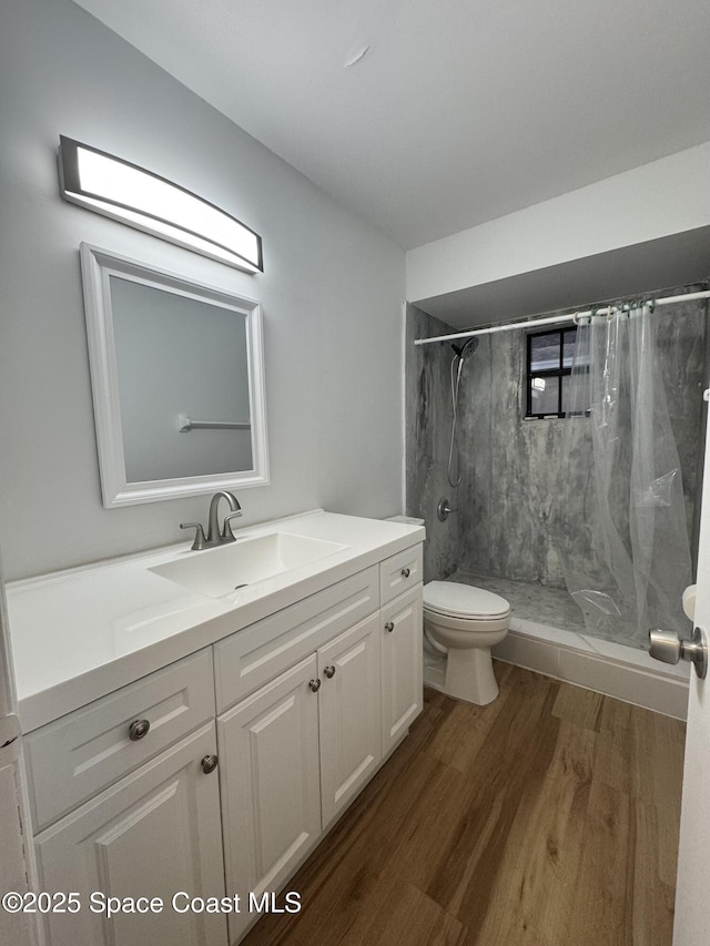 bathroom with wood-type flooring, toilet, a shower with shower curtain, and vanity