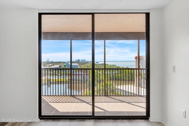 entryway featuring expansive windows, a water view, and a textured ceiling