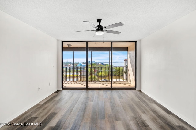 spare room with expansive windows, ceiling fan, hardwood / wood-style floors, and a textured ceiling