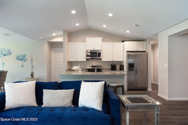 kitchen featuring light stone counters, white cabinets, stainless steel appliances, and vaulted ceiling