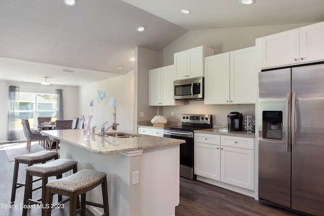 kitchen featuring stainless steel appliances, sink, a center island with sink, white cabinetry, and lofted ceiling