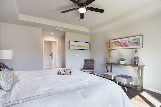 bedroom featuring a raised ceiling, connected bathroom, ceiling fan, and dark hardwood / wood-style floors