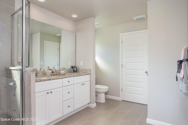 bathroom featuring tile patterned floors, vanity, a shower with shower door, and toilet