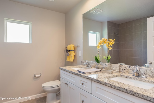 bathroom featuring tile patterned floors, vanity, tiled shower, and toilet