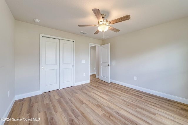 unfurnished bedroom with ceiling fan, light wood-type flooring, and a closet