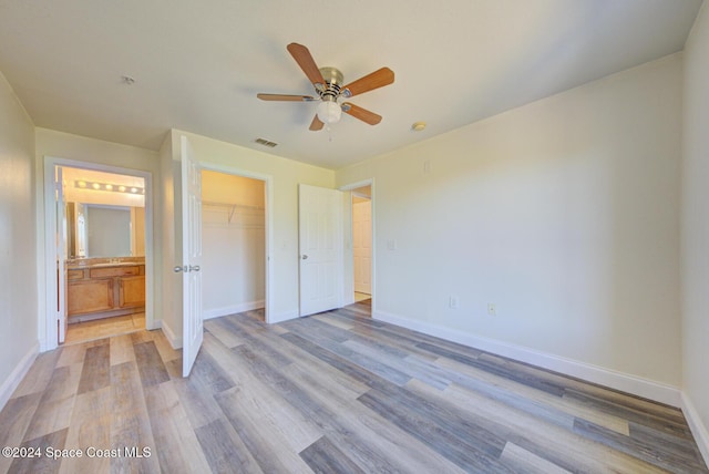 unfurnished bedroom featuring connected bathroom, ceiling fan, a closet, and light hardwood / wood-style floors