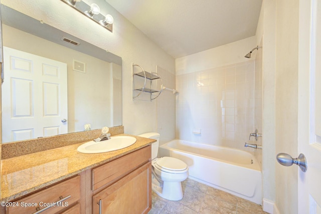 full bathroom with tile patterned floors, tiled shower / bath, vanity, and toilet