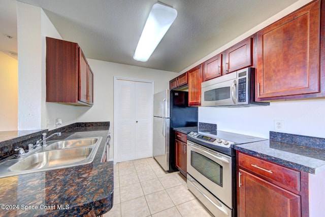 kitchen with a textured ceiling, light tile patterned flooring, sink, and stainless steel appliances