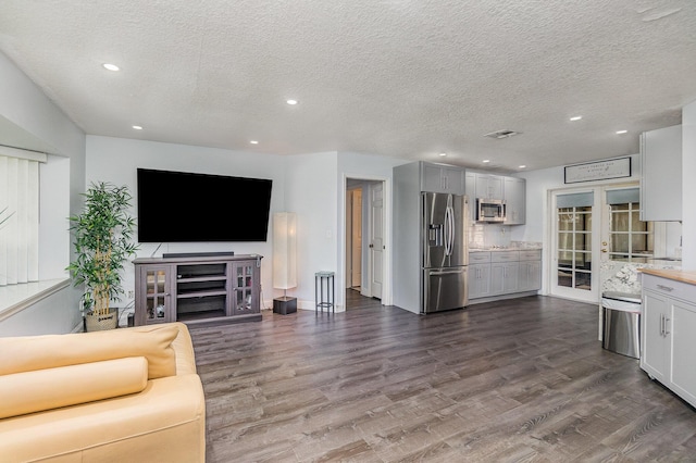 unfurnished living room featuring a textured ceiling, dark hardwood / wood-style flooring, and french doors