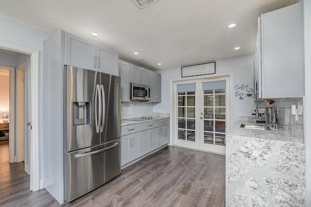 kitchen with french doors, sink, appliances with stainless steel finishes, tasteful backsplash, and light hardwood / wood-style floors