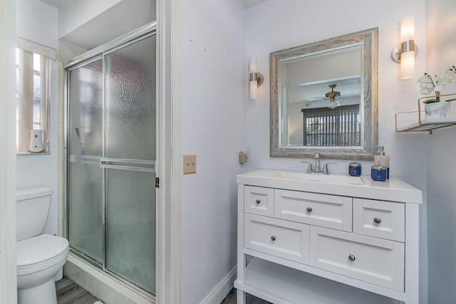 bathroom with ceiling fan, toilet, a shower with door, and vanity