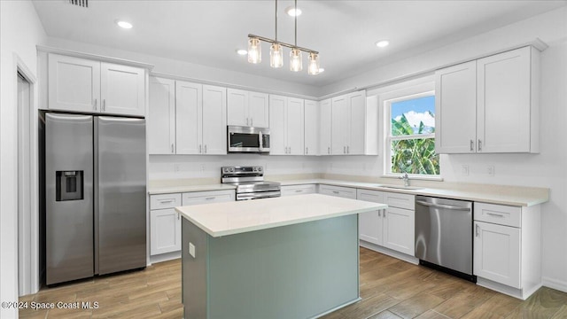 kitchen featuring stainless steel appliances, sink, white cabinets, a center island, and light hardwood / wood-style floors