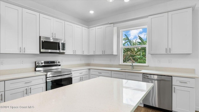 kitchen with light stone countertops, white cabinetry, sink, and appliances with stainless steel finishes