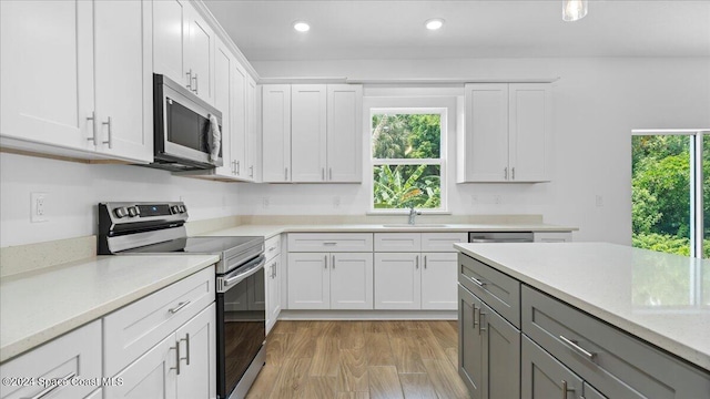 kitchen with white cabinets, sink, light wood-type flooring, and stainless steel appliances