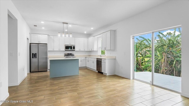 kitchen with a center island, light hardwood / wood-style flooring, appliances with stainless steel finishes, decorative light fixtures, and white cabinetry