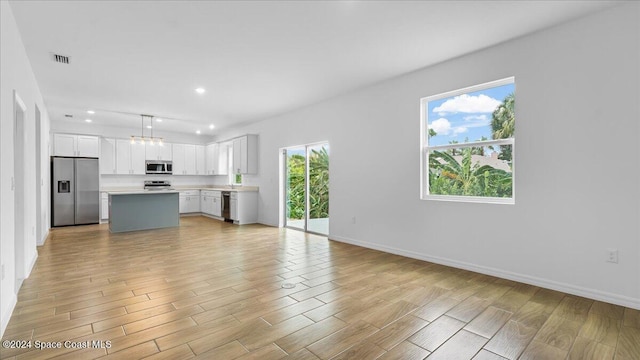 unfurnished living room with light hardwood / wood-style flooring and a notable chandelier