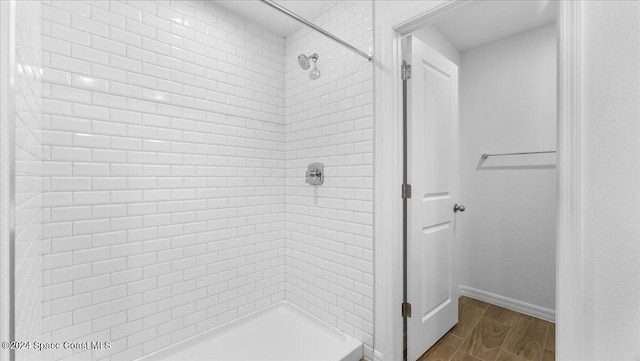 bathroom with wood-type flooring and a tile shower