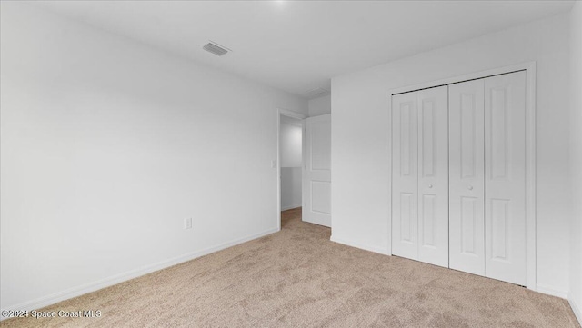 unfurnished bedroom featuring light carpet and a closet