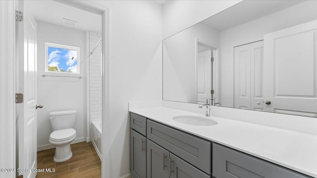 full bathroom featuring hardwood / wood-style floors, vanity, toilet, and washtub / shower combination