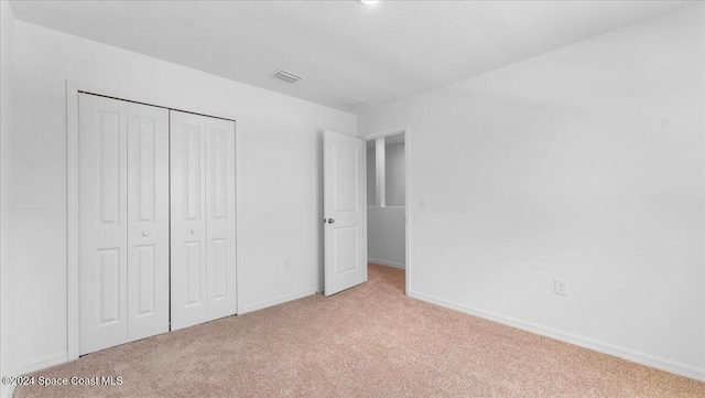 unfurnished bedroom featuring light carpet and a closet